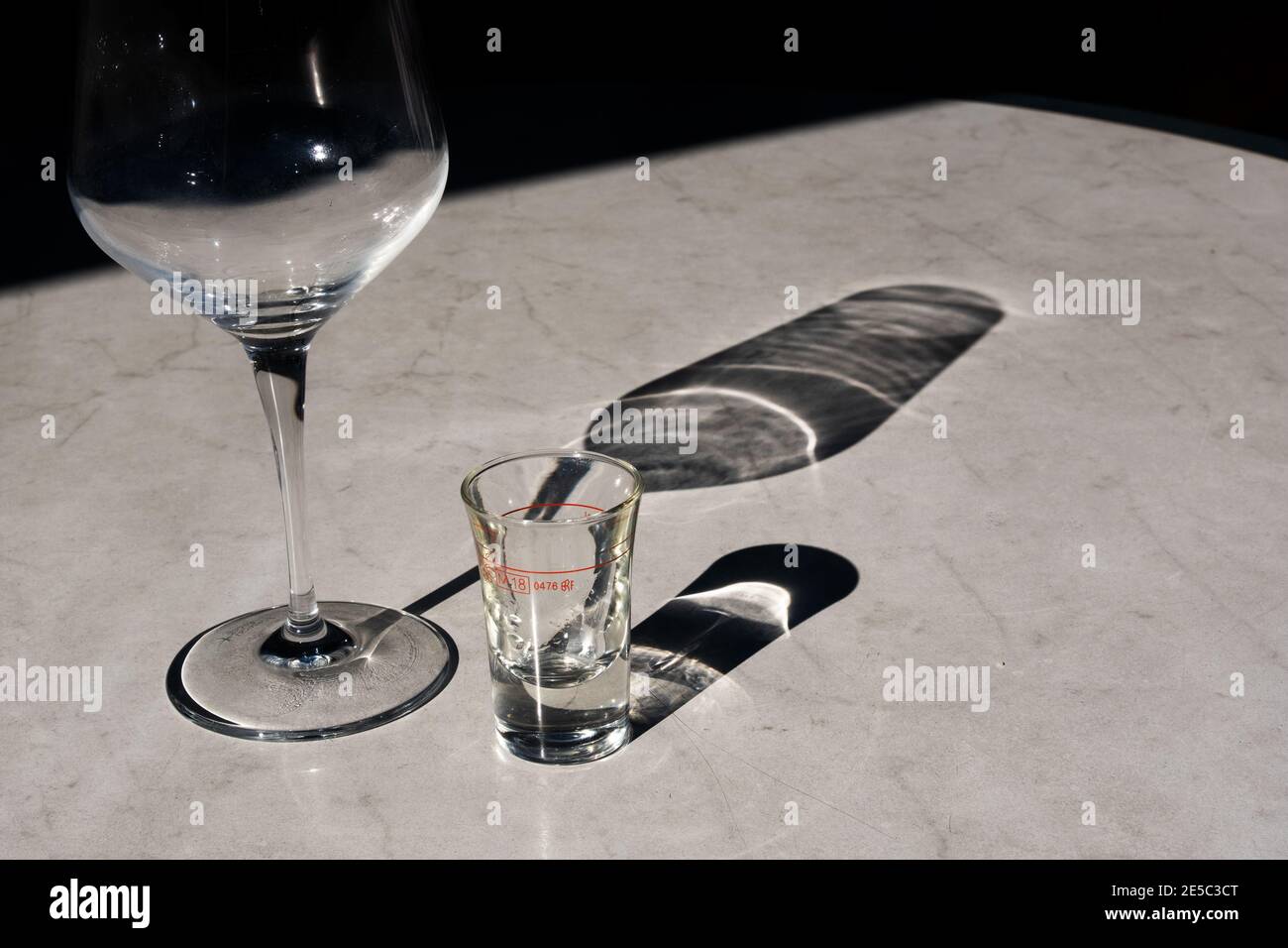 Tavolo di imitazione in marmo di plastica nella terrazza del ristorante dopo cena con Bicchiere di vino vuoto e antipasto vuoto Ouzo schnapps bicchiere con bella ombra orizzontale Foto Stock