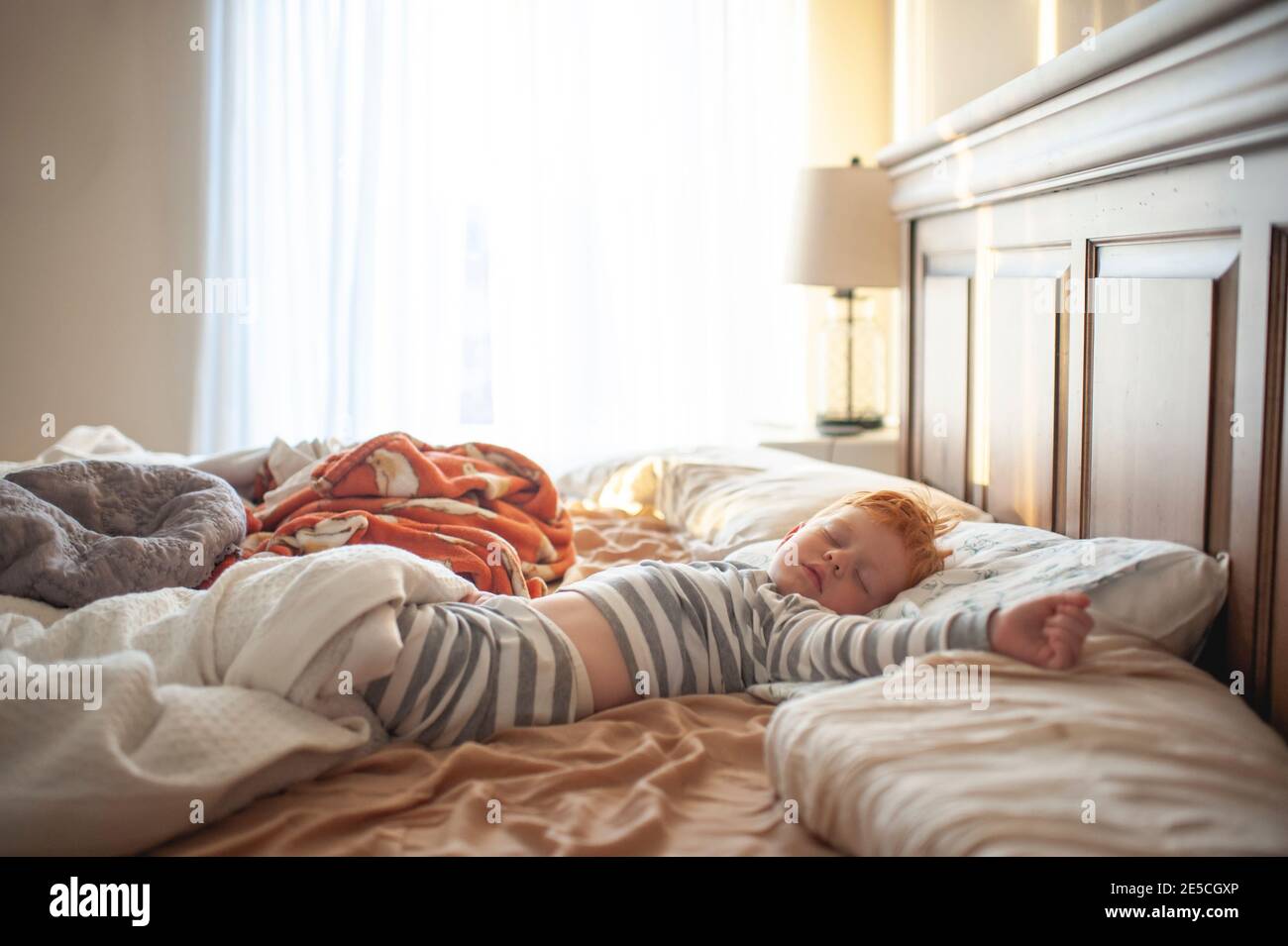 Il bambino di 3-4 anni dormiva nel letto dei genitori disordinato in bella luce Foto Stock