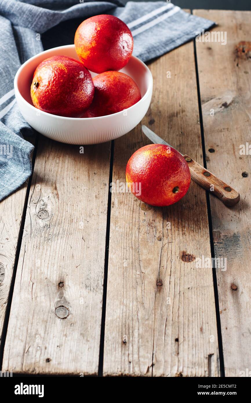 Arance fresche di sangue rosso in una ciotola su un tavolo di legno. Foto Stock