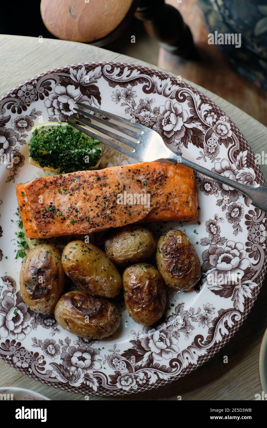 Filetto di salmone arrosto con patate novelle arrosto e spicchio di limone su un piatto vintage Foto Stock