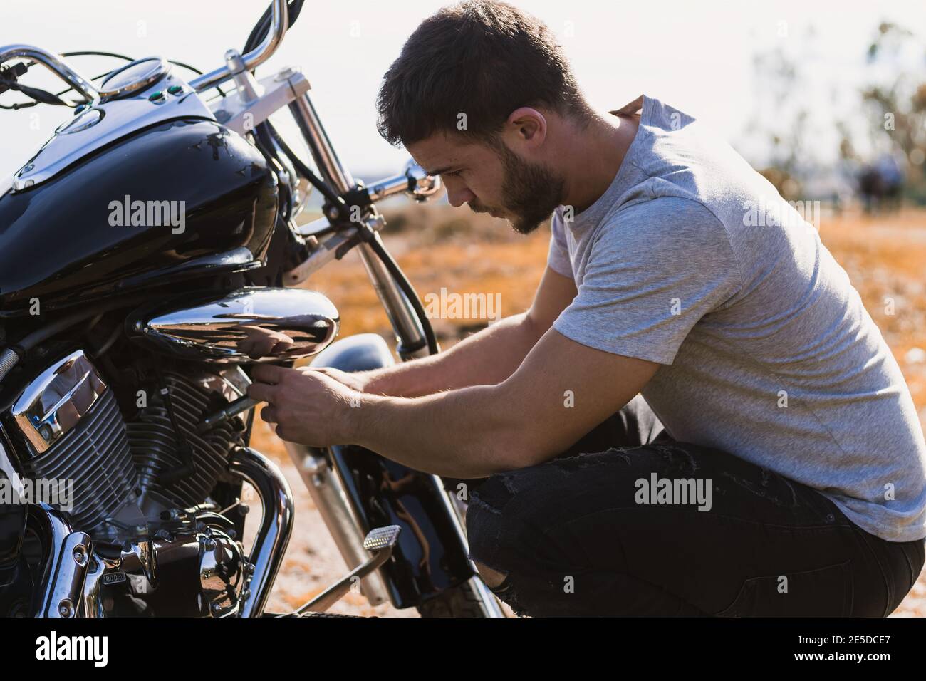 Motociclista accovacciato preoccupato per un guasto della motocicletta Foto Stock