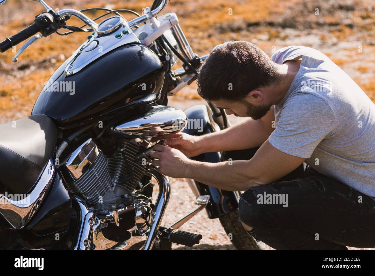 Motociclista accovacciato preoccupato per un guasto della motocicletta Foto Stock