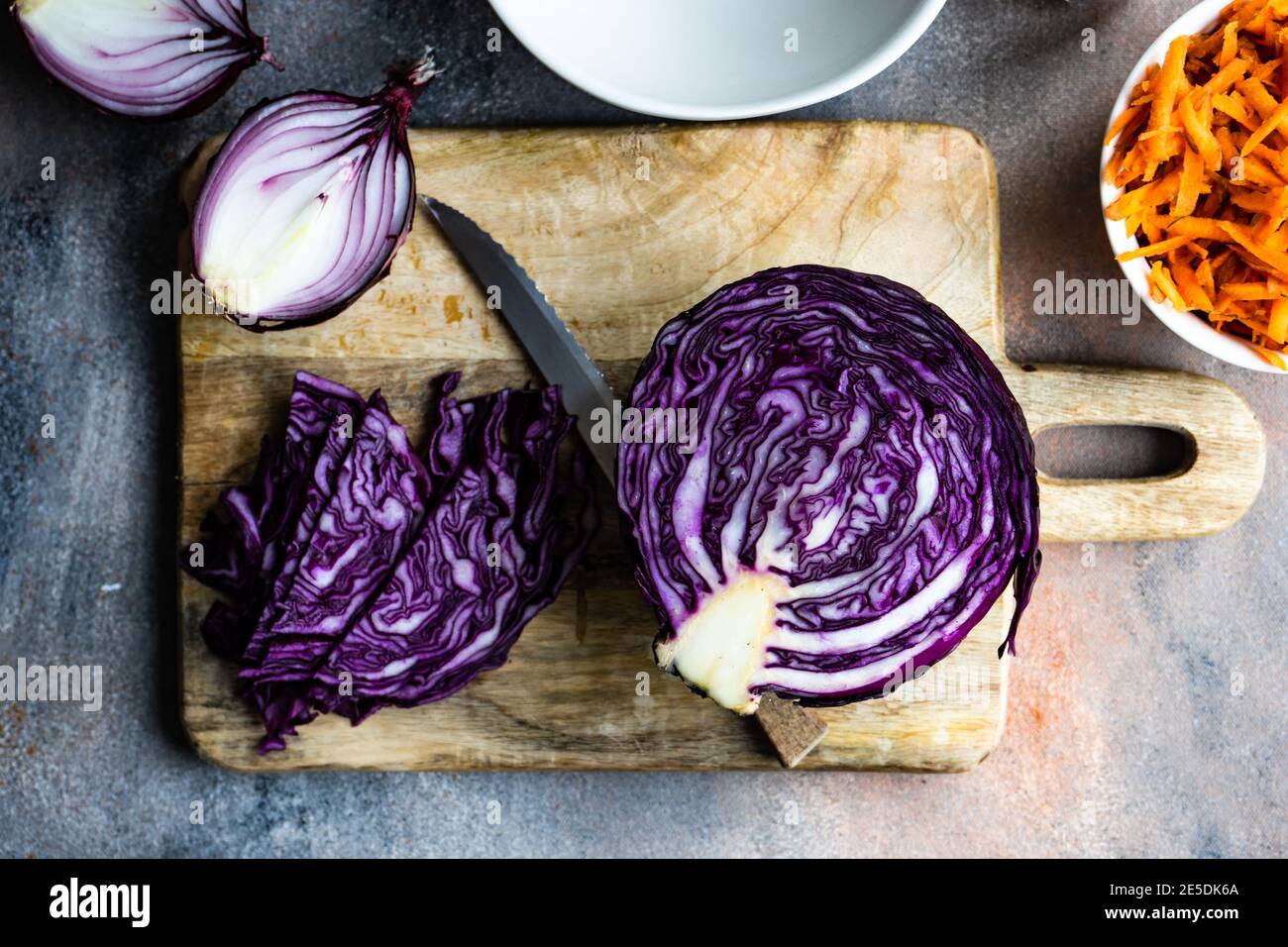 Carote fresche, cavolo e cipolle rosse su un tagliere Foto Stock