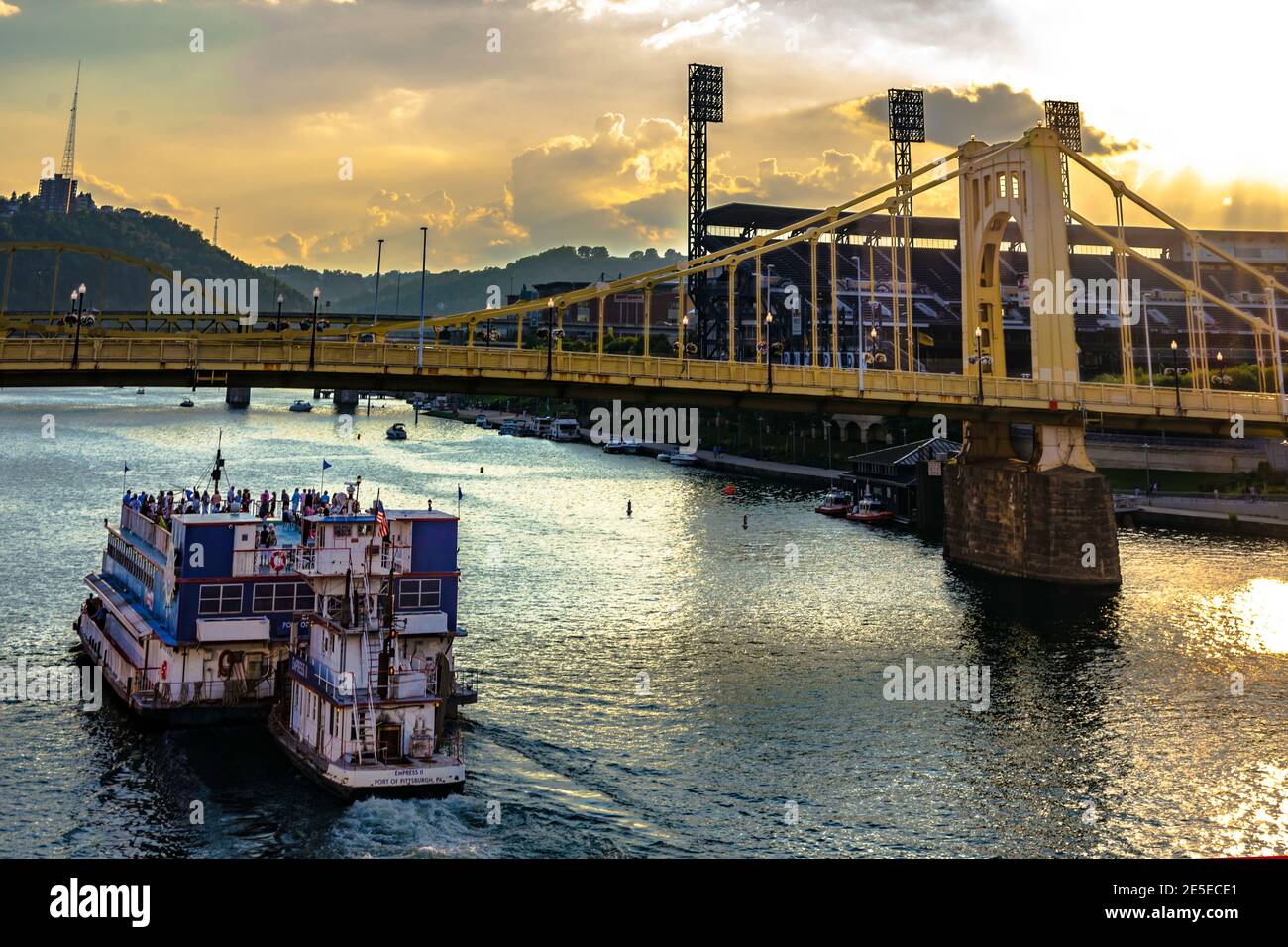 Pittsburgh, Pennsylvania, USA - 31 luglio 2016: Il battello fluviale Empress II naviga sul ponte Roberto Clemente e sul parco PNC mentre il sole tramonta su un caldo Foto Stock