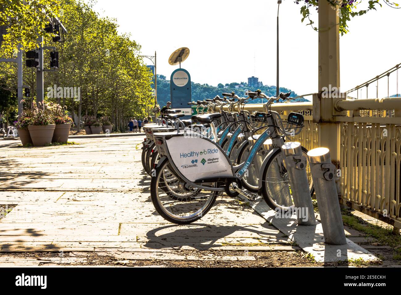 Pittsburgh, Pennsylvania, USA - 31 luglio 2016: Una fila di biciclette a noleggio Healthy Ride allineate sulla strada come i turisti camminano sullo sfondo. Foto Stock