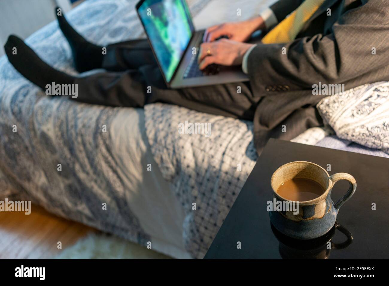 Uomo che lavora da casa in una tuta mani su computer portatile le chiavi del computer si siedono sul letto corona virus lavoro a casa Concept moderno ad alta vista MR Foto Stock