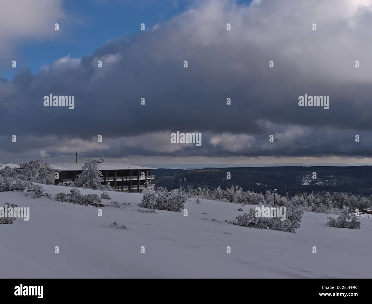 Splendida vista sulla collina di Schliffkopf, in Germania, sulle montagne della Foresta Nera, con edificio alberghiero e prato innevato con alberi congelati in neve profonda. Foto Stock
