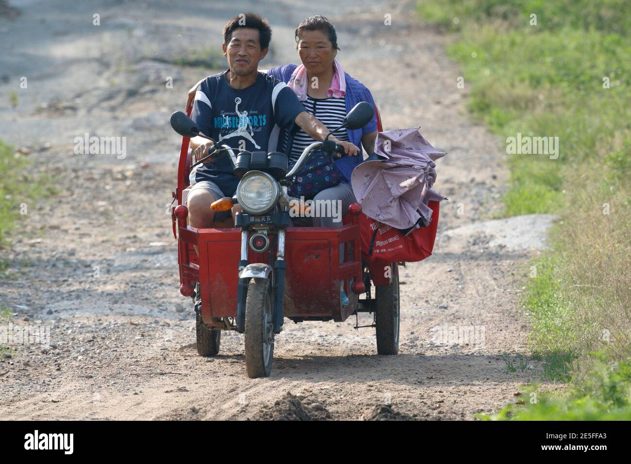 Uomo e donna che cavalcano sul triciclo a motore, vista frontale, Dongzhai, Provincia di Henan, Cina 23 giugno 2016 Foto Stock