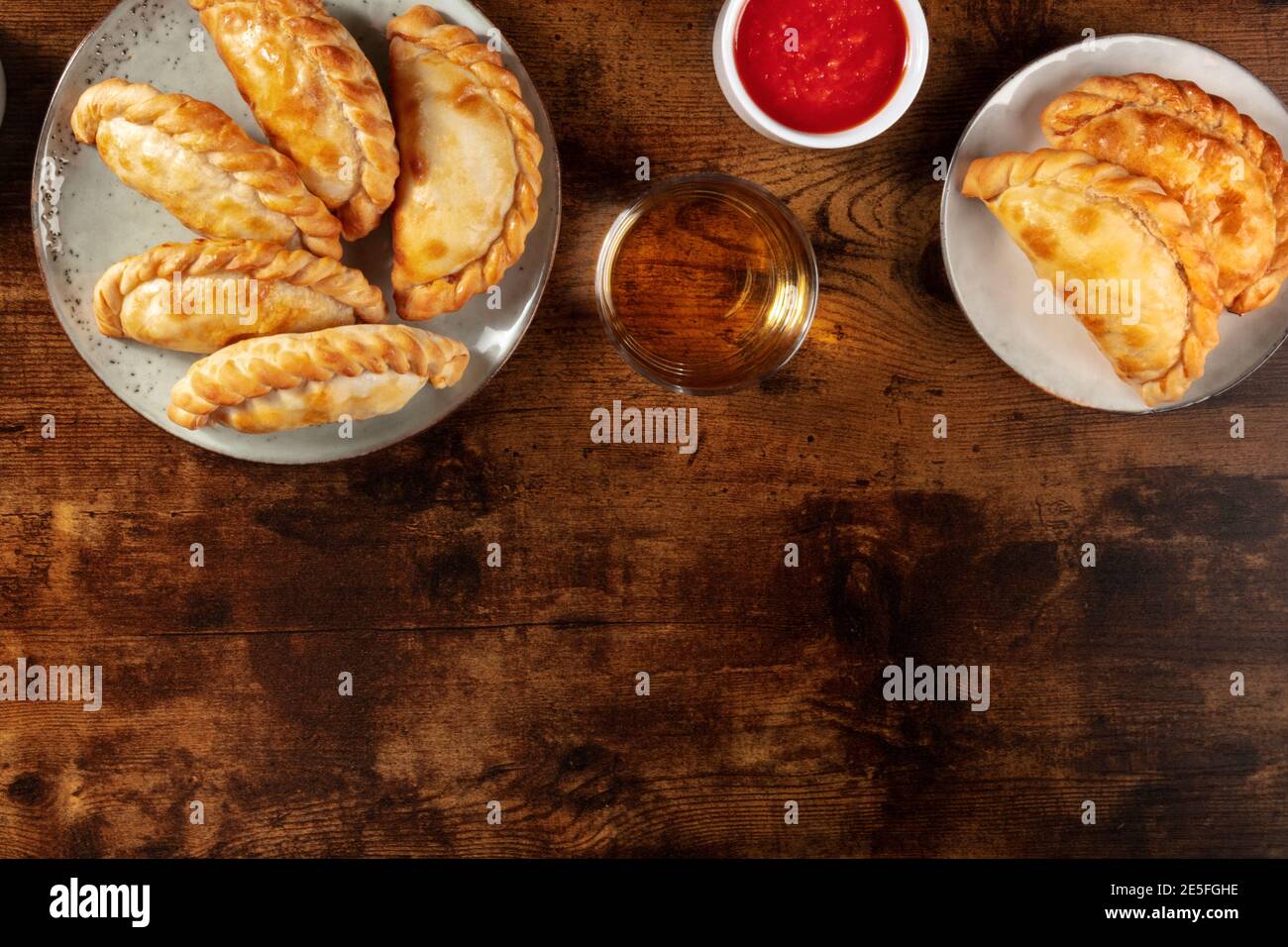 Empanadas con salsa e vino, girato dall'alto con spazio di copia su uno sfondo di legno rustico scuro Foto Stock