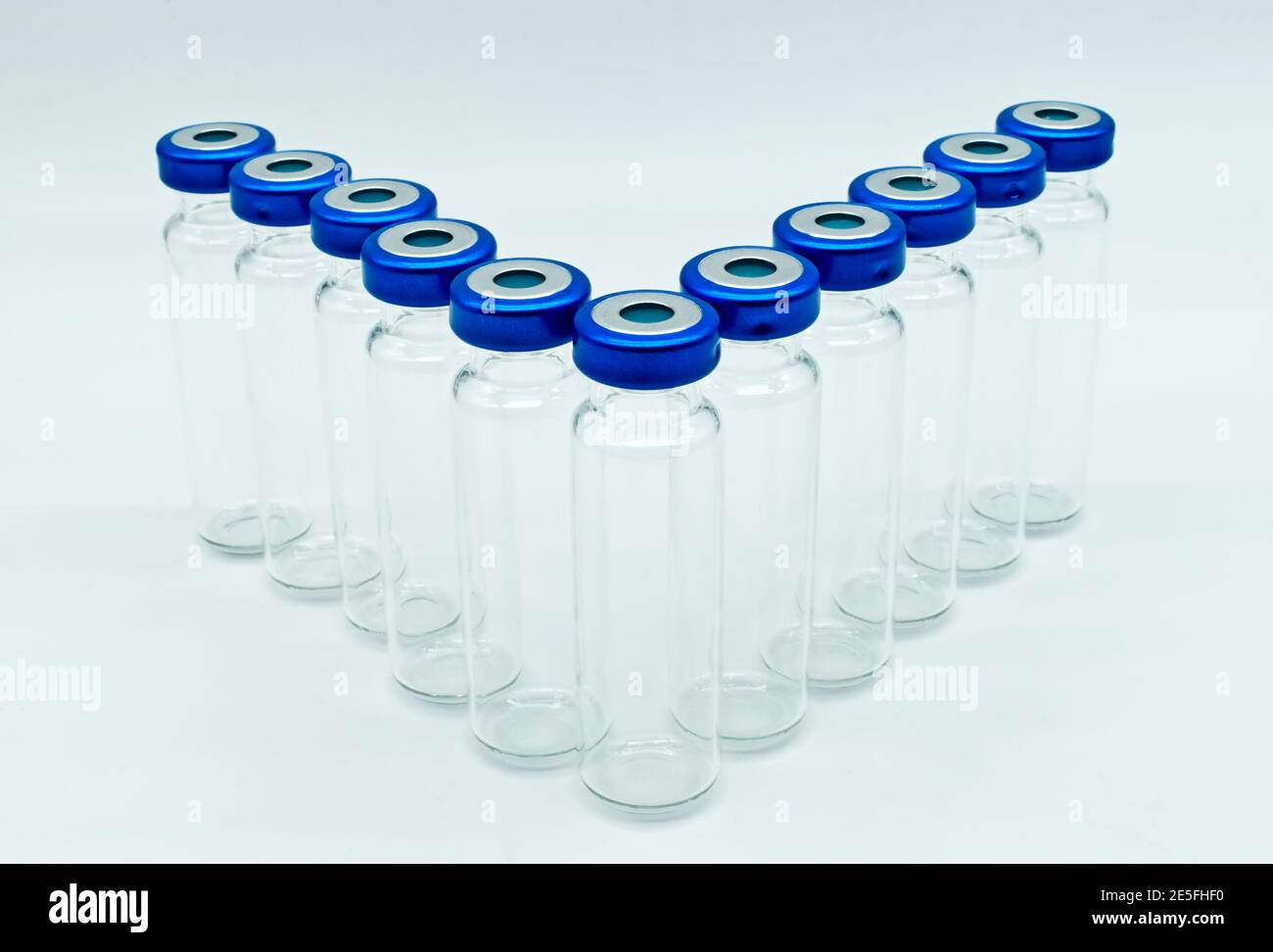 Fila di flaconcini medici in vetro trasparente per iniezione con coperchi sigillati blu, isolati su sfondo bianco. Foto Stock