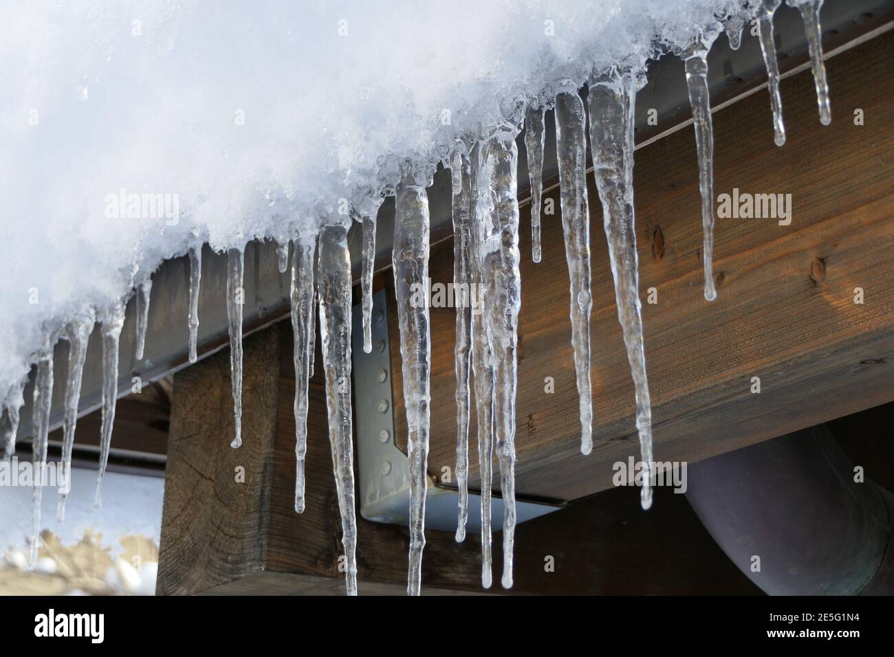 All'esterno in inverno lunghi icicles appesi alle travi del tetto Foto Stock