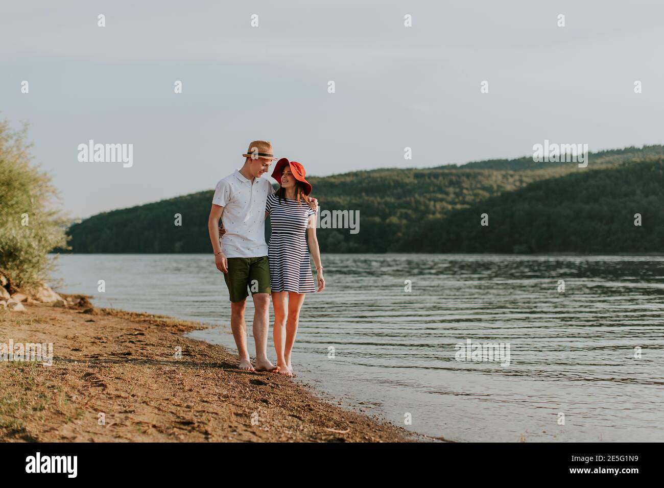 Una coppia piena d'amore camminando lungo la spiaggia in una bella serata estiva. Ritratto di giovane donna e uomo che abbracciano mentre si va a piedi sul essere Foto Stock