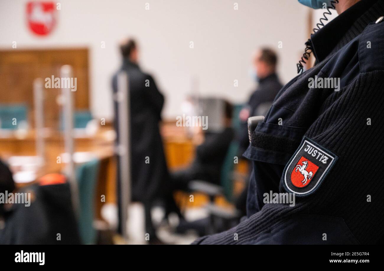 28 gennaio 2021, bassa Sassonia, Lüneburg: Il convenuto (M) copre il suo volto con un cartella nel tribunale distrettuale. Si dice che l'uomo di 20 anni abbia ucciso due persone e ferito gravemente un'altra persona a Neuenkirchen, nel distretto di Heidekreis, nel giugno 2020. Per coprire le tracce, si dice che l'accusato abbia messo fuoco la casa delle vittime. Foto: Philipp Schulze/dpa Foto Stock