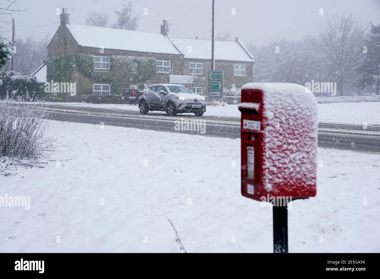 Un'automobile che fa il relativo senso lungo una strada coperta di neve in Slaley, Northumberland, poichè parti del Regno Unito potrebbe essere blanketed con fino a sette pollici (20cm) di neve nei due giorni successivi, mentre una fascia di pioggia pesante potrebbe anche innescare l'inondazione, ha detto i previsori. Data immagine: Giovedì 28 gennaio 2021. Foto Stock