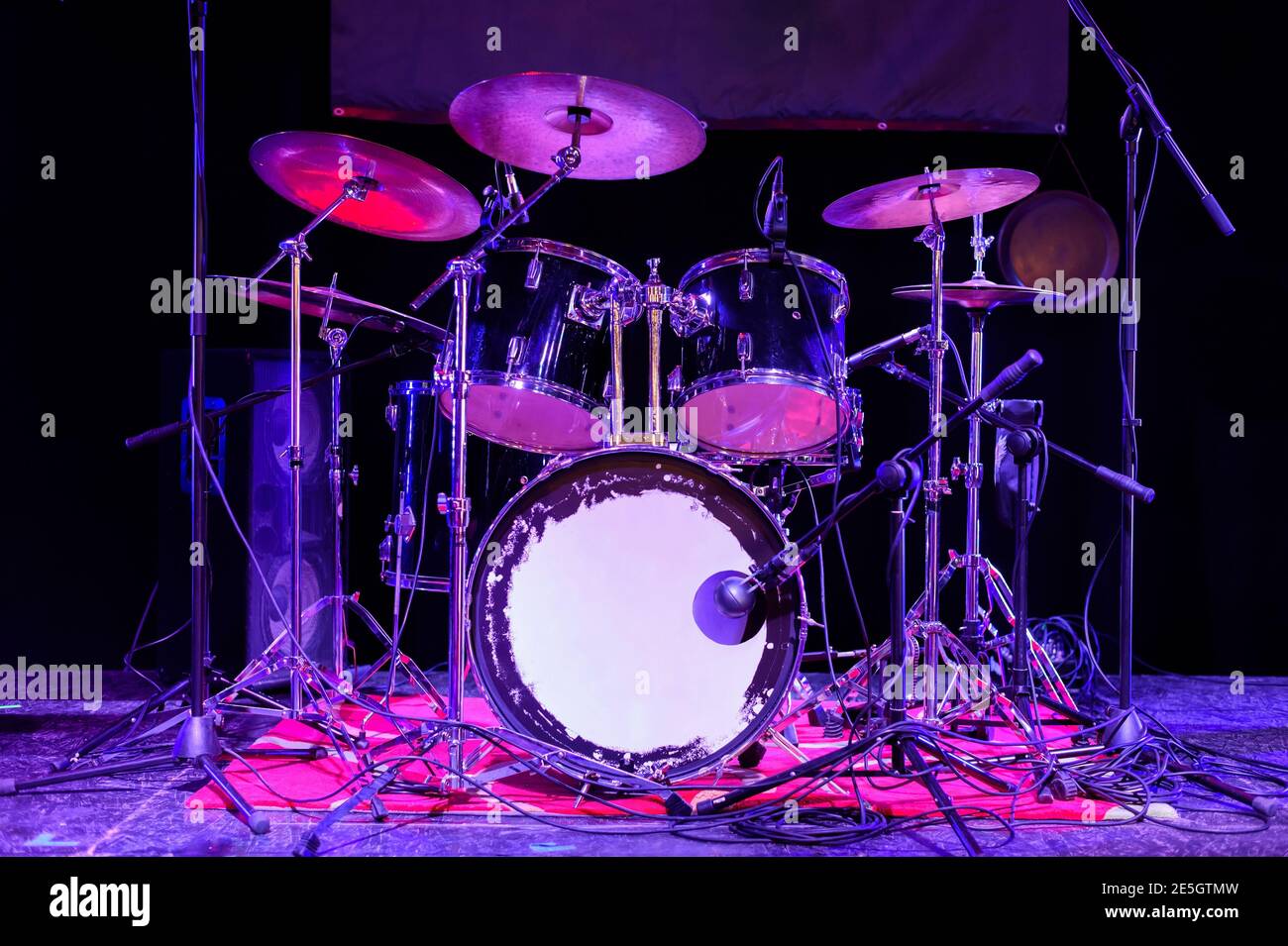 Il tamburo impostato sul palco. Il drum kit si trova in uno spazio buio ed è illuminato dalla luce al neon. Foto Stock