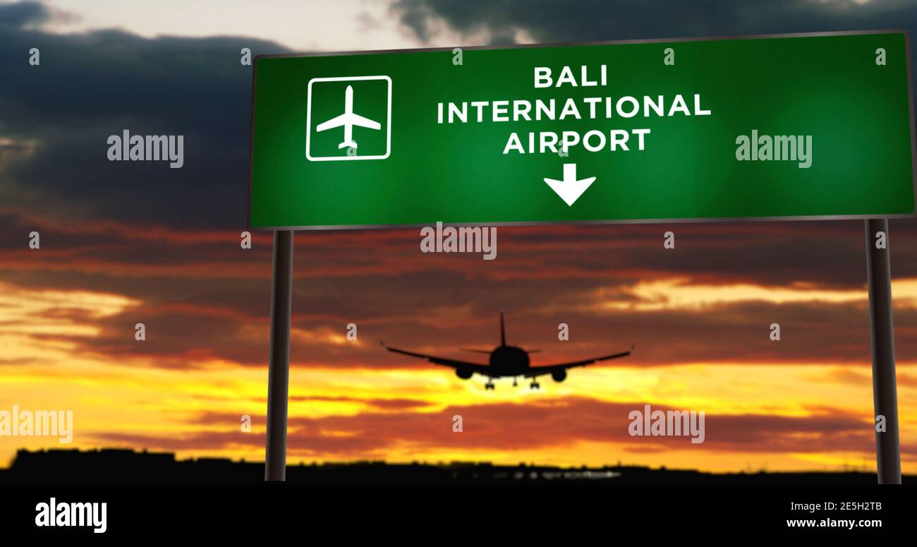 Atterraggio di silhouette di aeroplano a Bali, Indonesia. Arrivo in città con cartello con la direzione dell'aeroporto e tramonto sullo sfondo. Viaggio e trasporto concep Foto Stock
