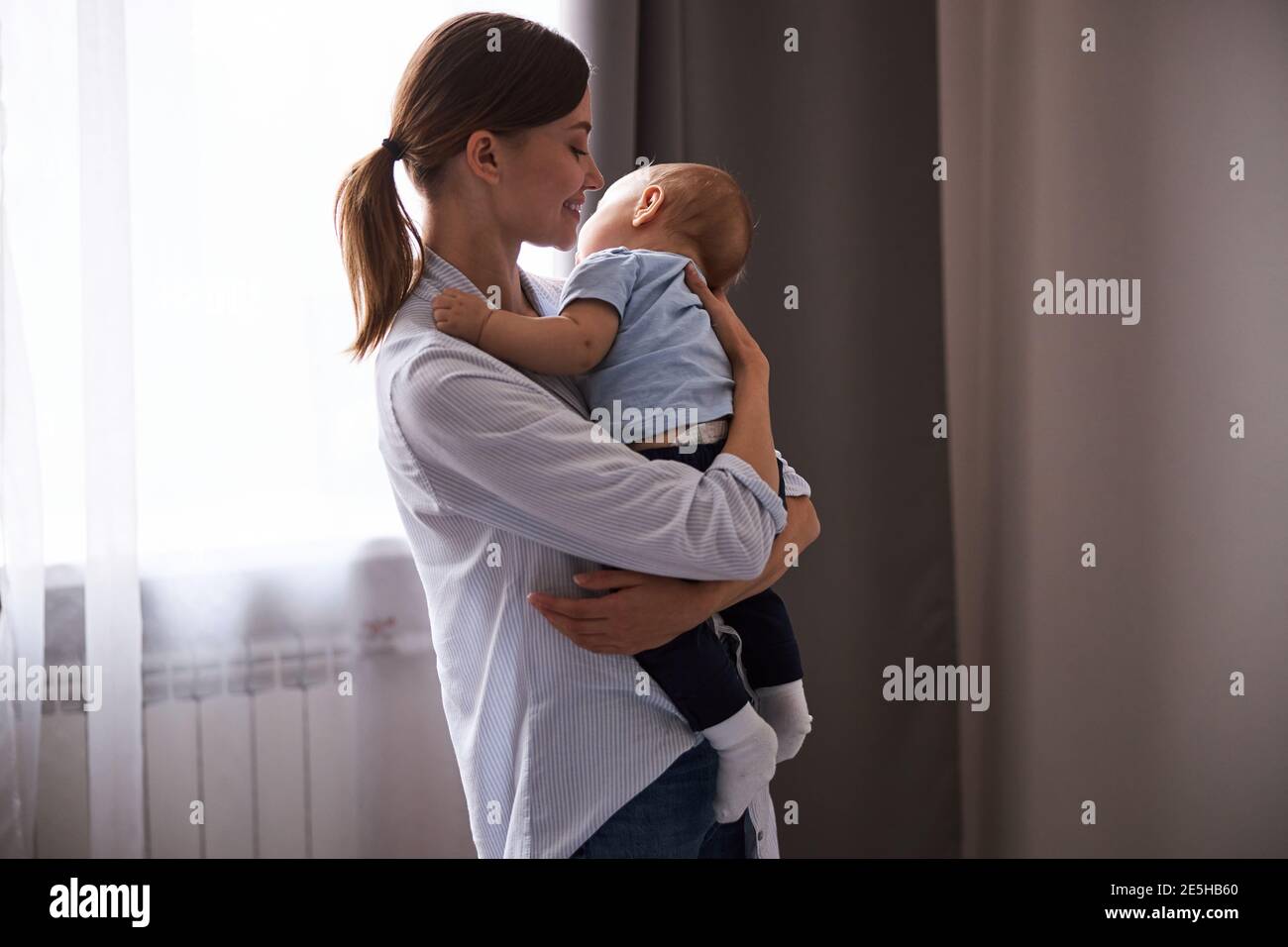 Positivo felice giovane genitore lulling suo bambino Foto Stock