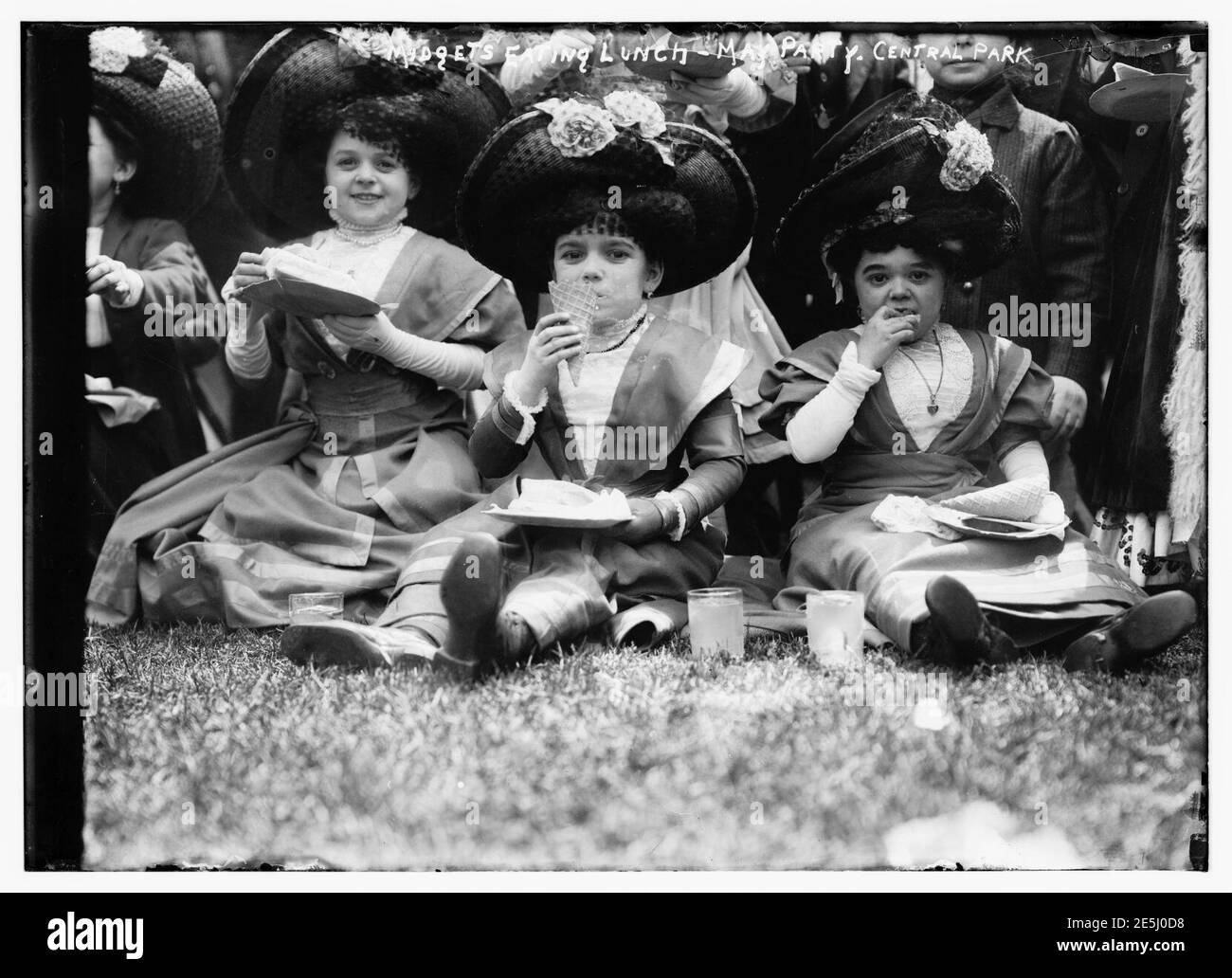 Midgets mangiare pranzo - May party - Central Park. Tre midget seduti sull'erba. Foto Stock