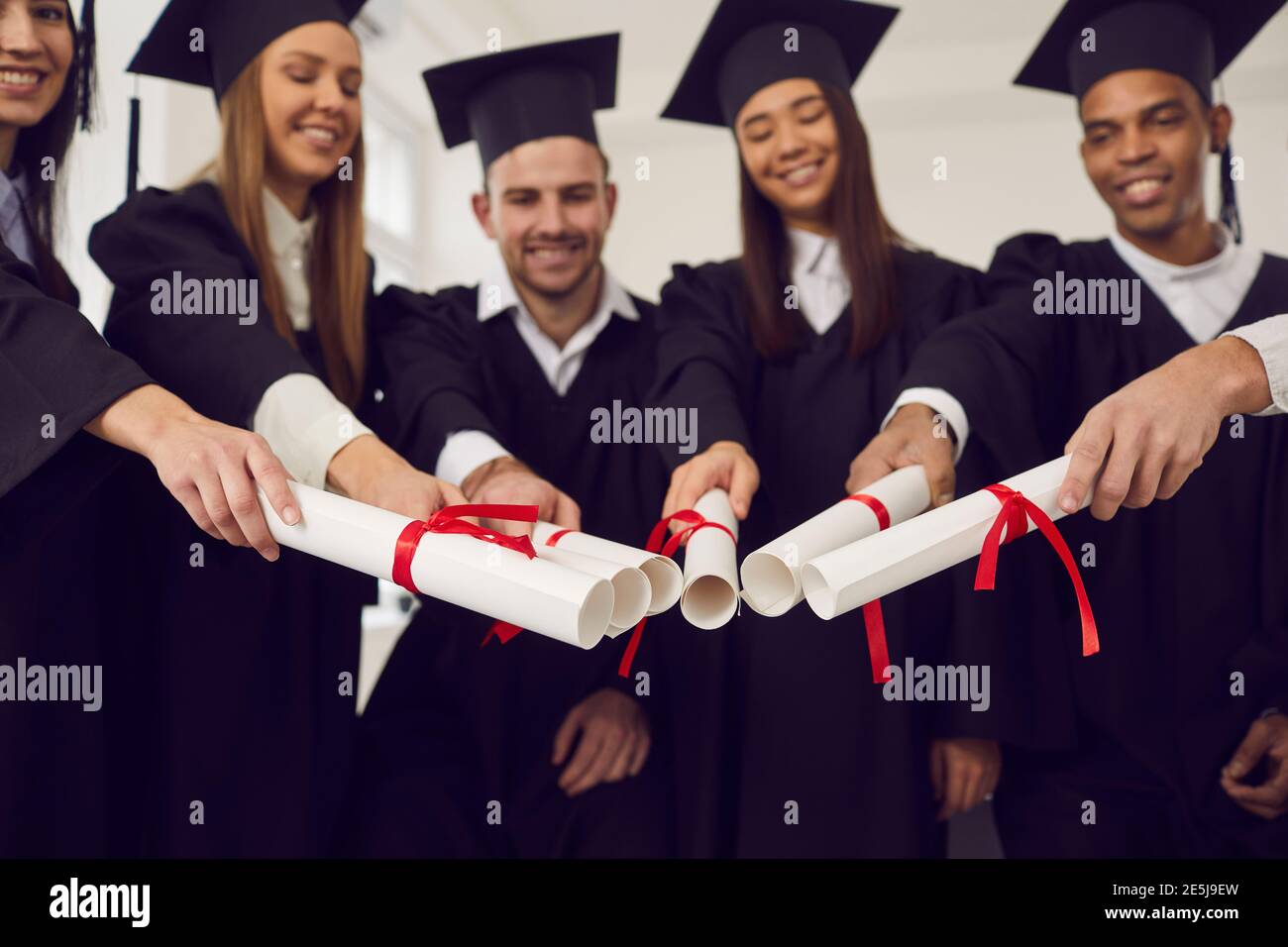 Diplomati amici unendo i diplomi insieme come simbolo di unità, successo comune, squadra, successo Foto Stock