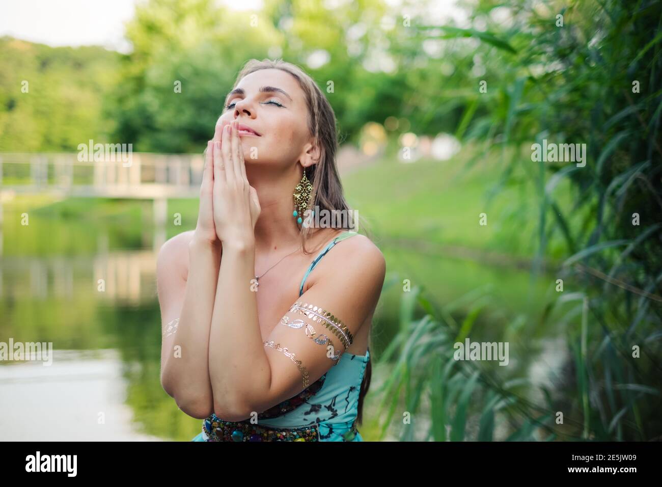 Bella giovane donna che prega all'aperto al tramonto Foto Stock