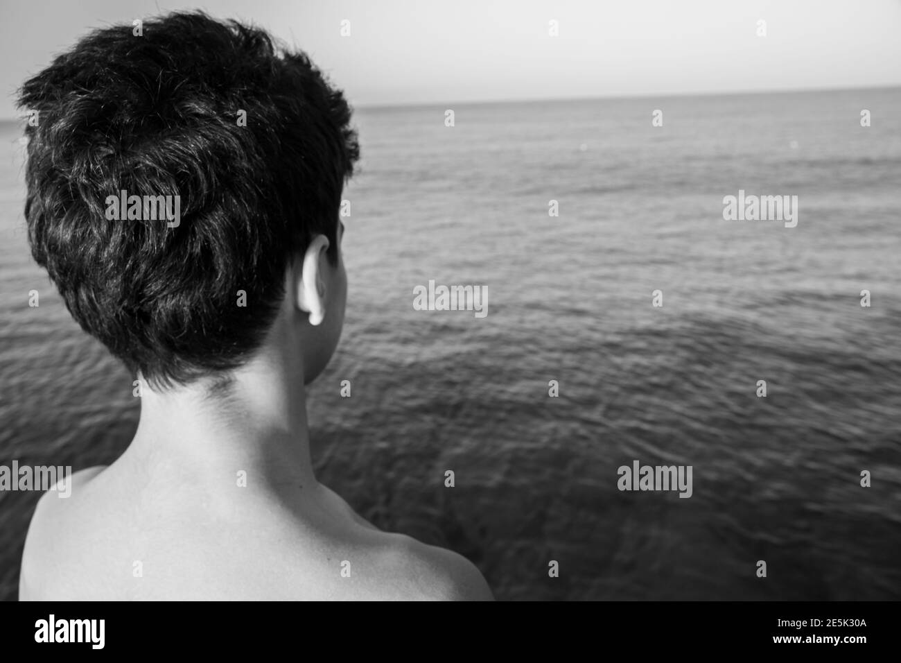 ragazzo seduto al mare da solo a guardare l'acqua Foto stock - Alamy