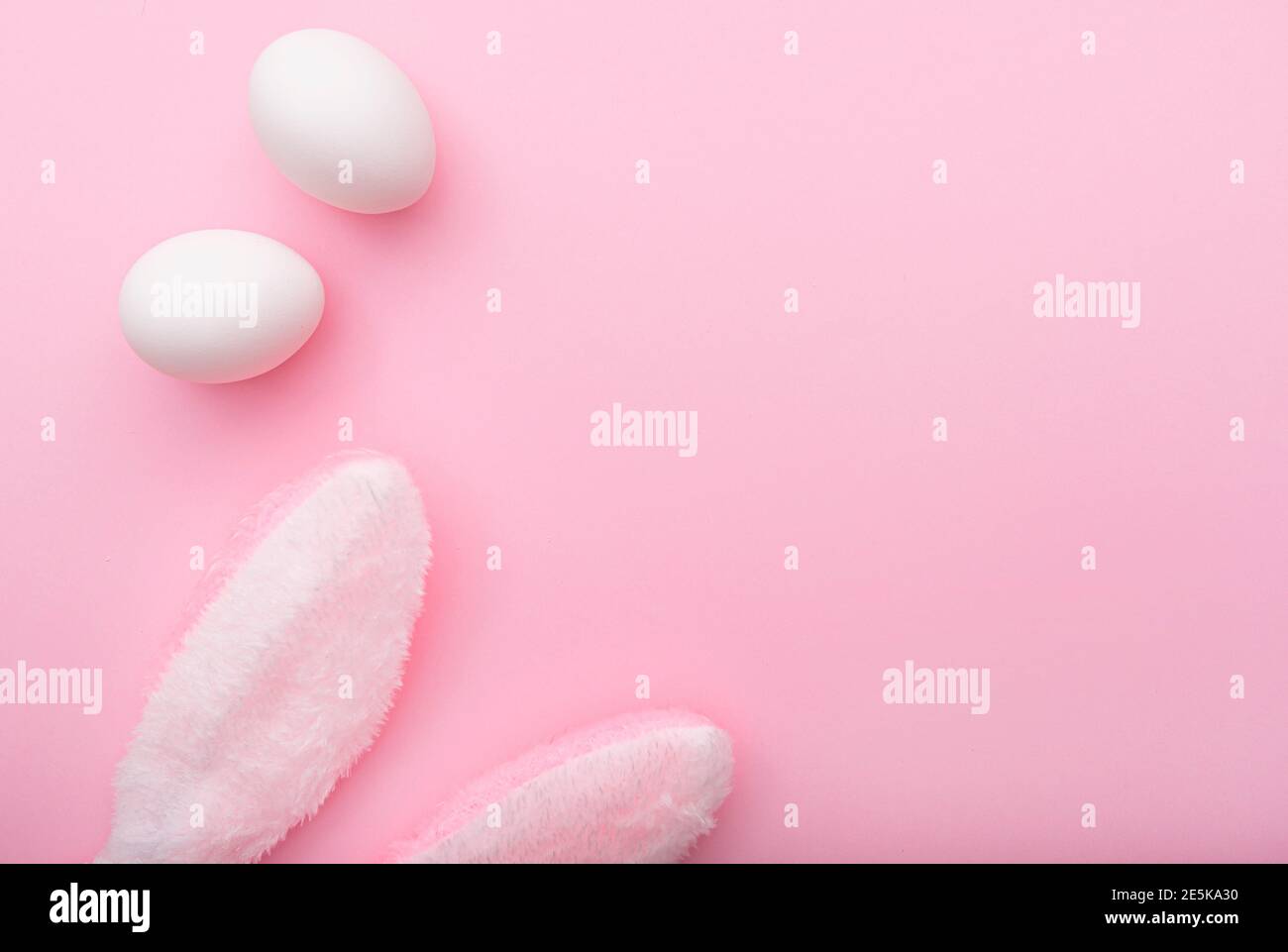 Uova bianche e orecchie di coniglio su sfondo rosa, Pasqua piatto minimo, vista dall'alto, spazio per il testo Foto Stock