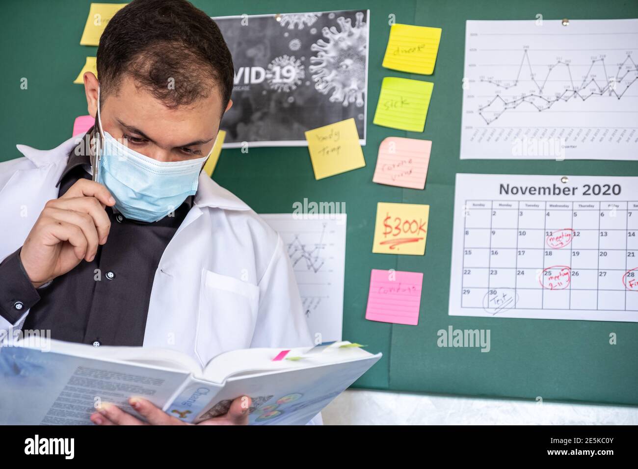 Medico maschile indossando la sua maschera e controllando il suo libro Foto Stock