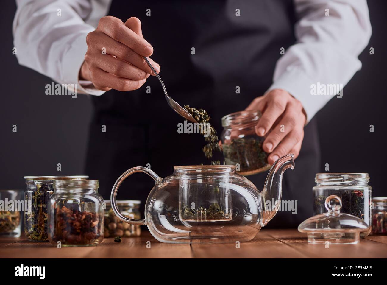 Barista che mette le foglie di tè verde in una teiera Foto Stock
