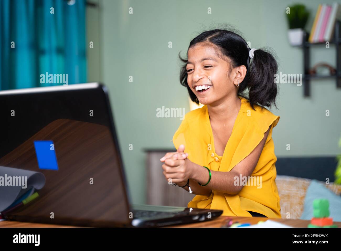 Felice bambino giovane ragazza disabile ridendo e aggrappando guardando divertenti video online sul notebook a casa - concetto di i bambini si divertono durante il tempo libero Foto Stock