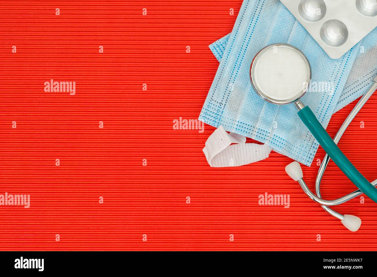 Stetoscopio e pillole su uno sfondo rosso vista dall'alto con spazio libero Foto Stock
