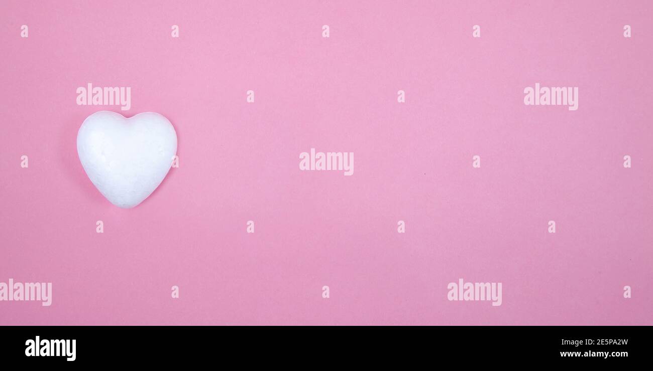 Un cuore bianco su sfondo rosa. Amiamo la vista dall'alto e lo spazio per le copie. Foto Stock