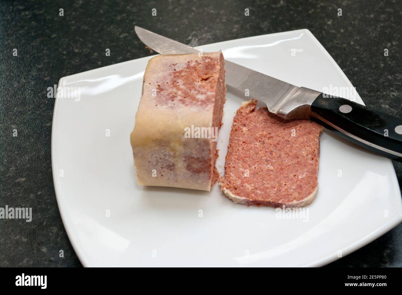 Affettato manzo Corned su un piatto bianco con un coltello Foto Stock