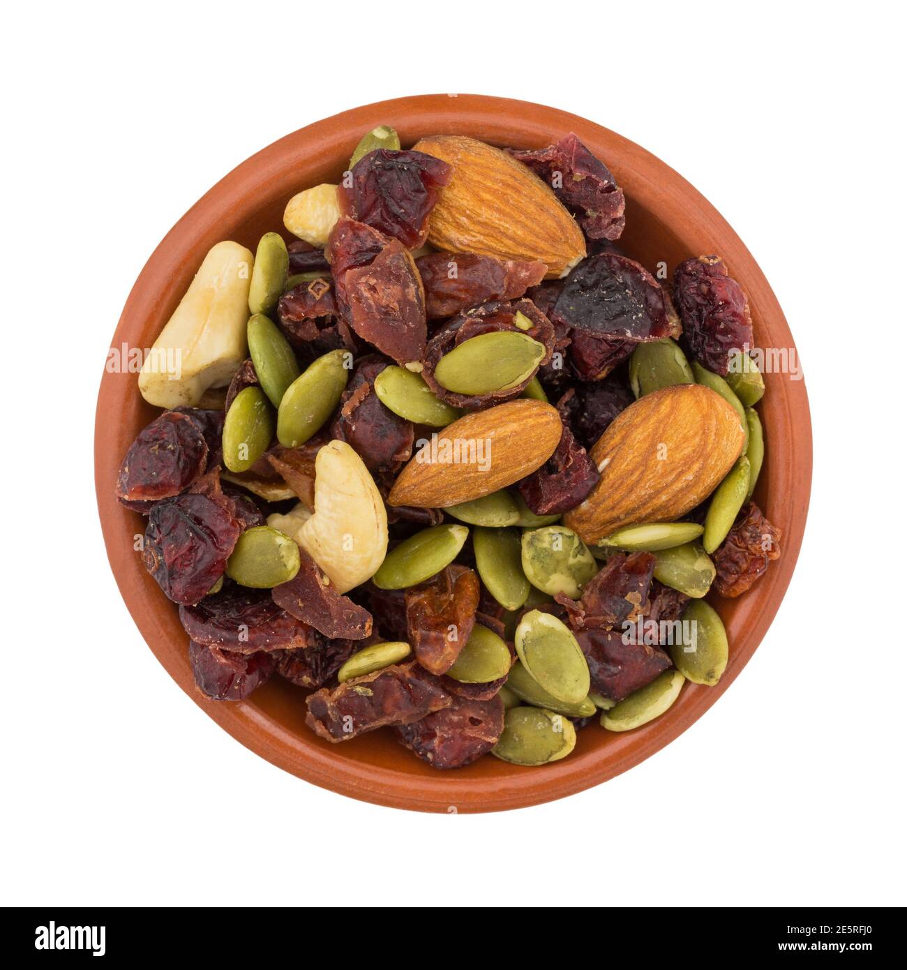 Vista dall'alto di una piccola porzione di semi, noci e frutta in una ciotola isolata su sfondo bianco. Foto Stock