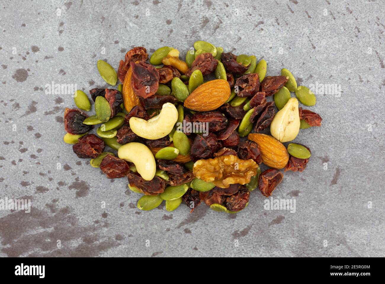 Vista dall'alto di una piccola porzione di semi, noci e frutta su sfondo grigio. Foto Stock