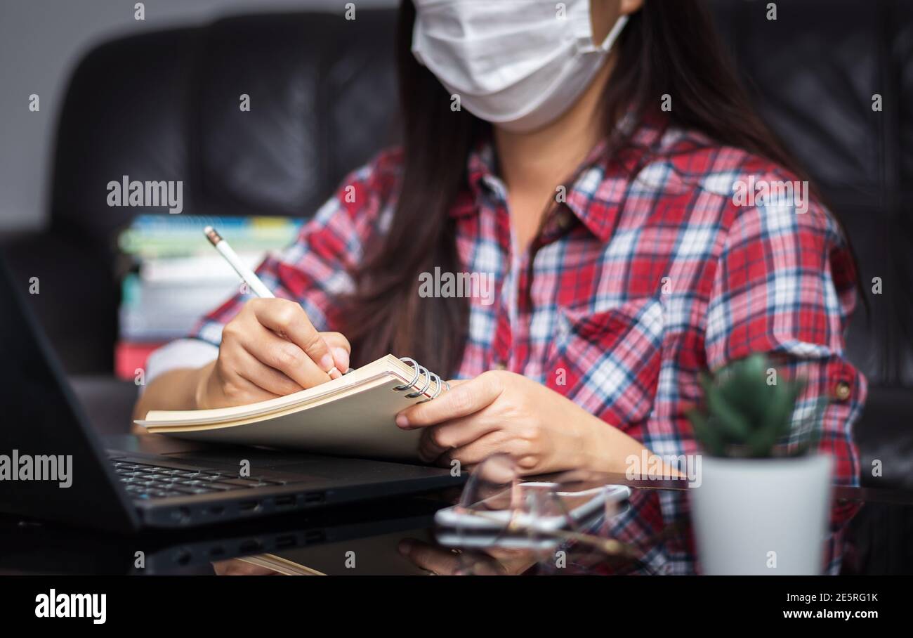 nuovo normale, lavoro da casa, studio online, homeschooling, formazione a distanza. studente indossare igienico proteggere maschera di protezione studio on-line ascoltare lezione Foto Stock