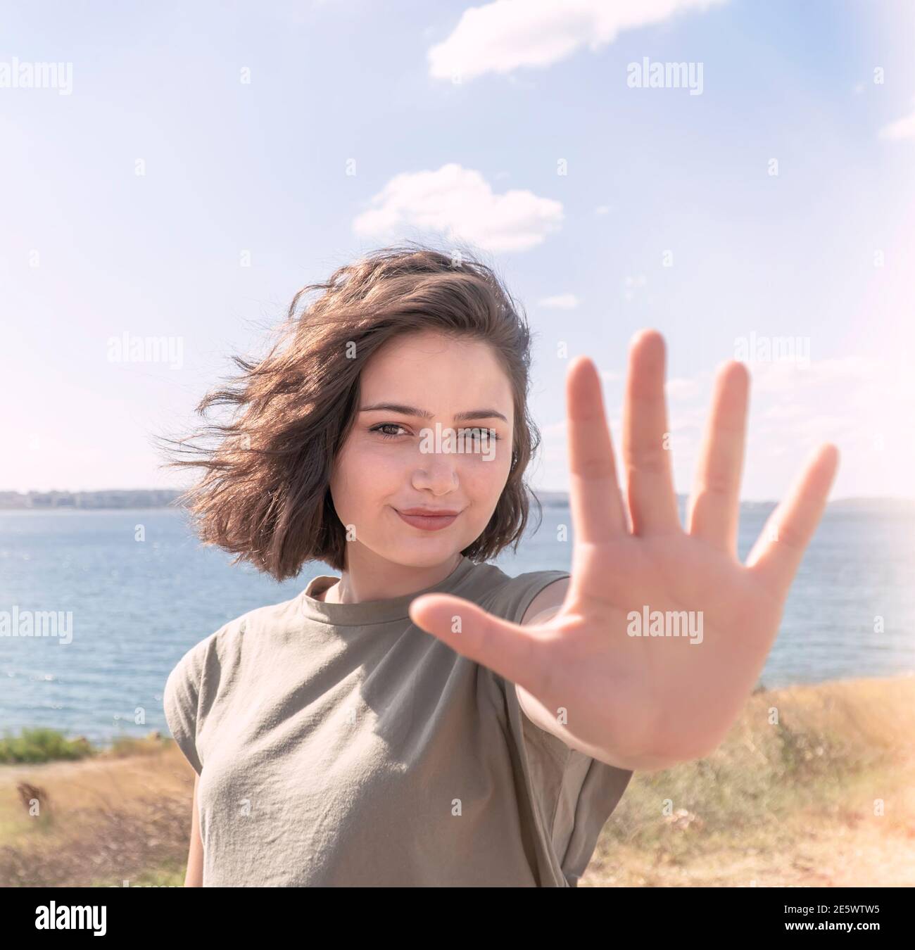 Bella giovane donna felice facendo segno di stop con la mano. Foto Stock
