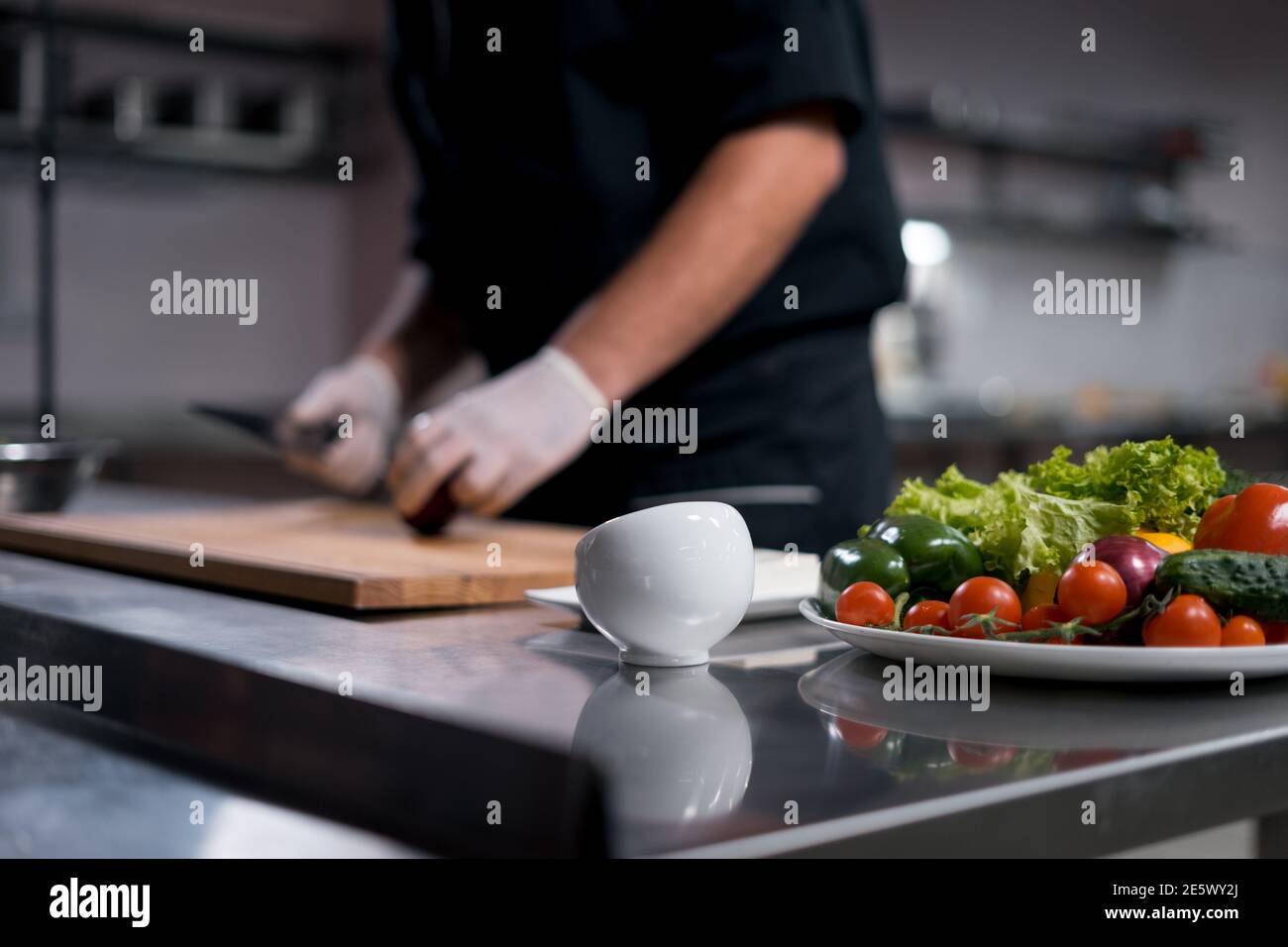 cuoco cuoco in guanti medici preparare insalata greca o tritare verdure in cucina Foto Stock