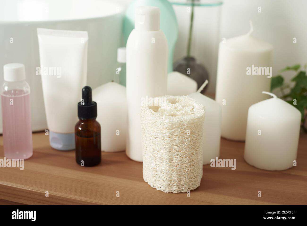 Loofah, crema, siero e lozione scrubber sul piano di appoggio accanto al lavello bianco in bagno. Pulizia e idratazione della pelle la sera. Foto Stock