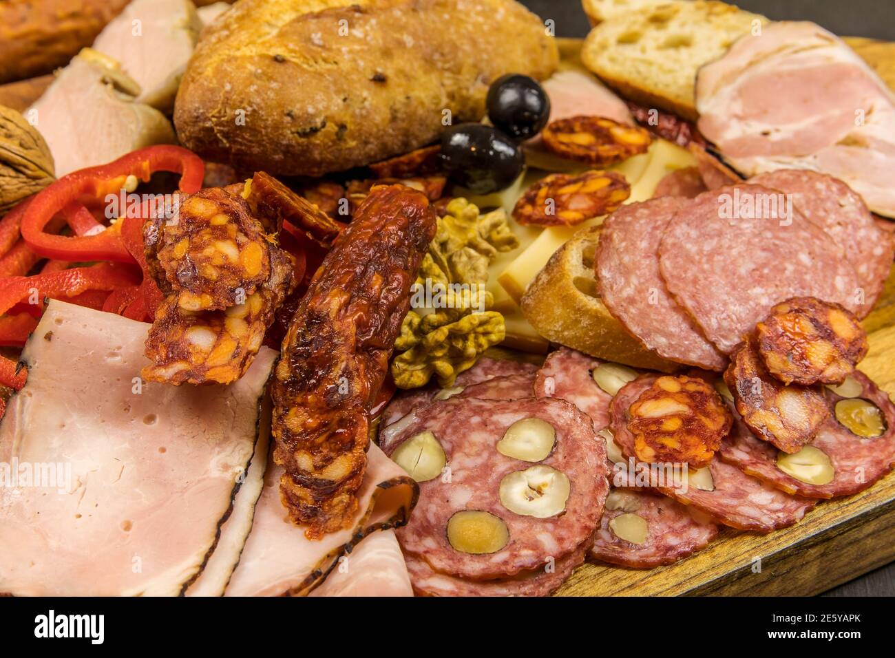 Vari tipi di salame, speck e salsicce su un tavolo di legno. Cibo spazzatura grasso. Carne affumicata. Concetto di obesità. Sovrappeso. Foto Stock
