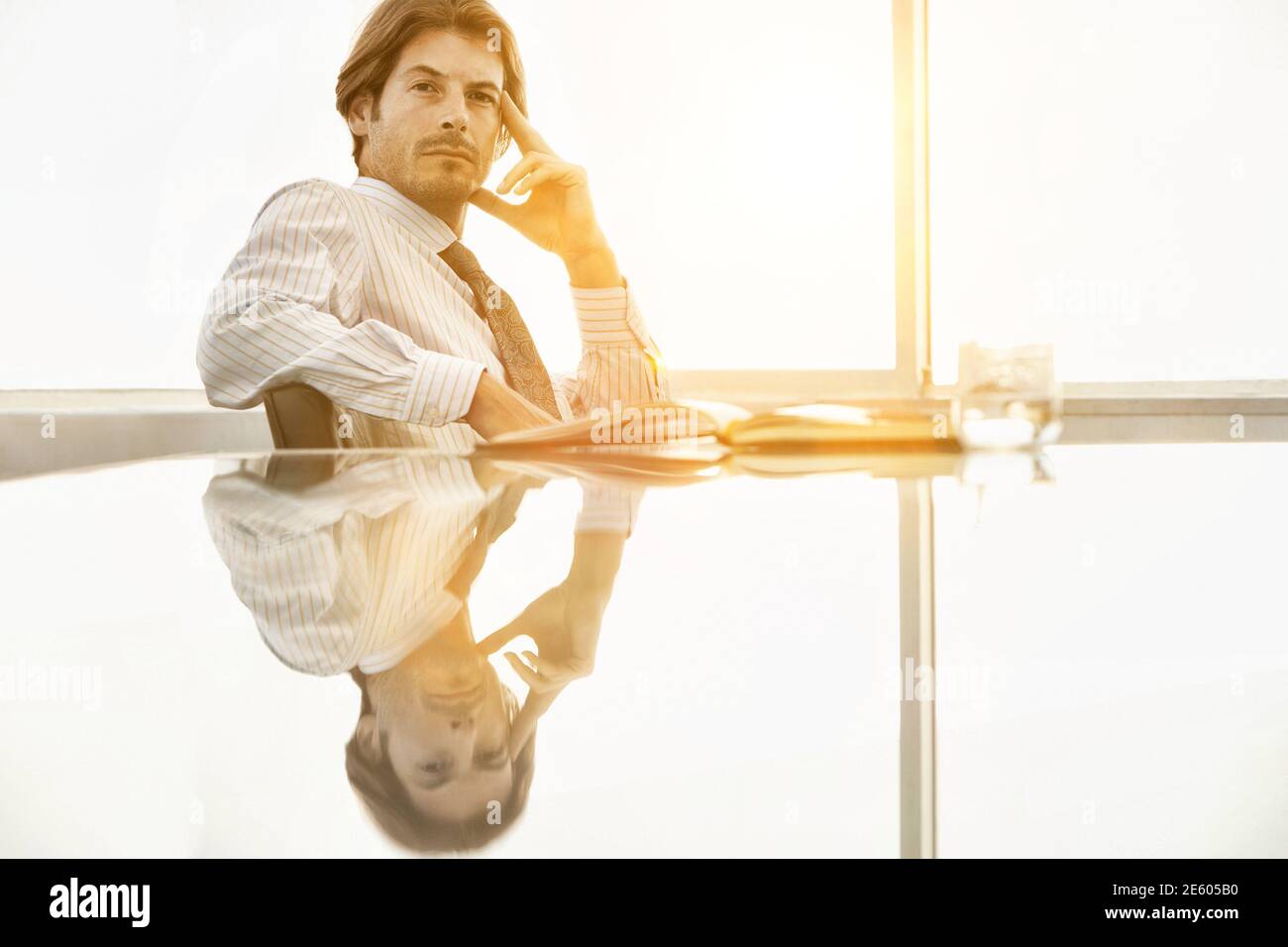 Ritratto di imprenditore fiducioso con la mano sulla faccia seduti ad un tavolo per conferenza Foto Stock