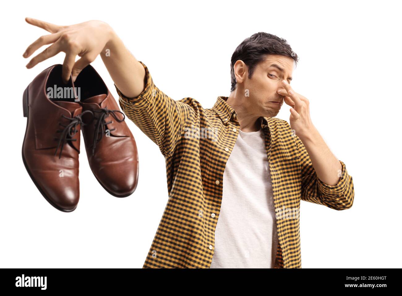 Uomo che blocca il naso e tiene un paio di puzzolenti scarpe isolate su sfondo bianco Foto Stock
