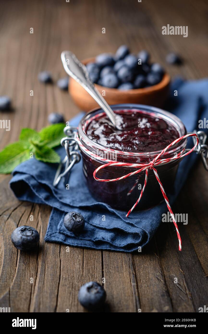 Sana marmellata di mirtillo in un vaso di vetro servito con frutti di bosco freschi, serviti su tavolo di legno Foto Stock
