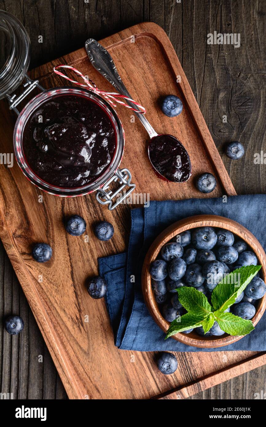 Sana marmellata di mirtillo in un vaso di vetro servito con frutti di bosco freschi, serviti su tavolo di legno Foto Stock
