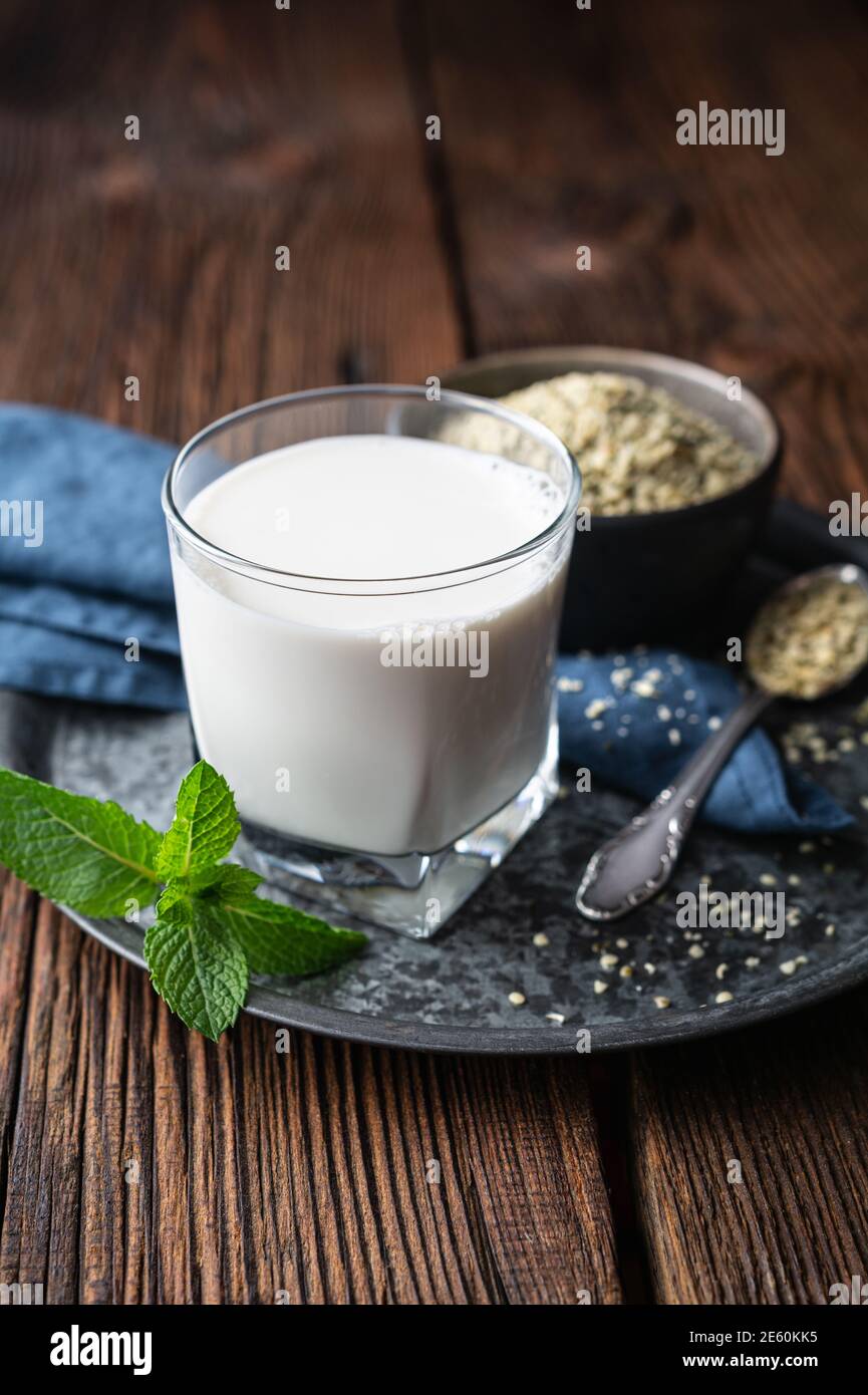 Una bottiglia di latte fresco di semi di canapa senza latte per vegani su sfondo di legno, decorato con menta Foto Stock