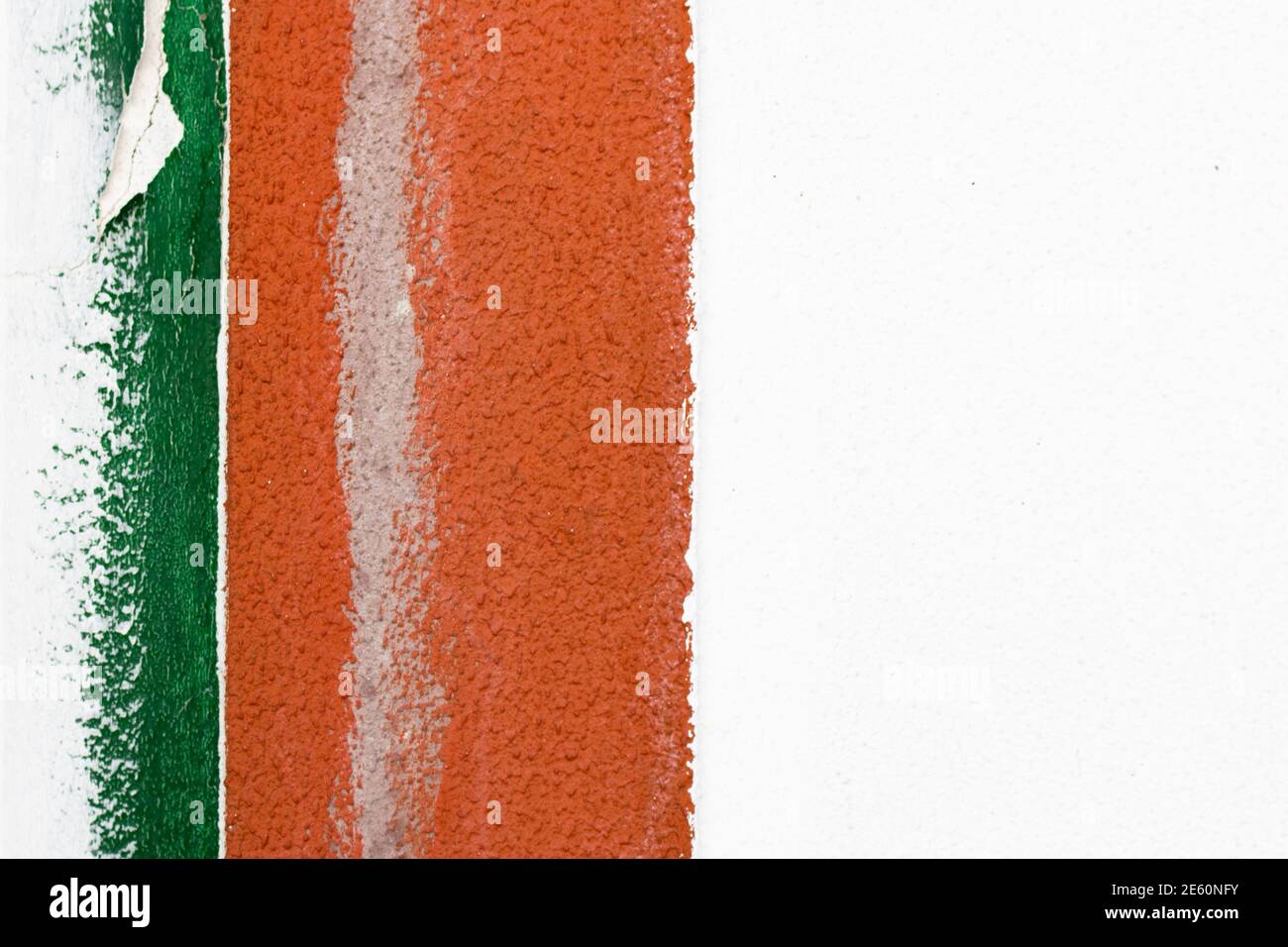 Particolare di una vecchia parete in cemento bianco con bordo di due strisce verticali verniciate di colore verde e arancione sul lato sinistro del telaio. Disegno astratto Foto Stock