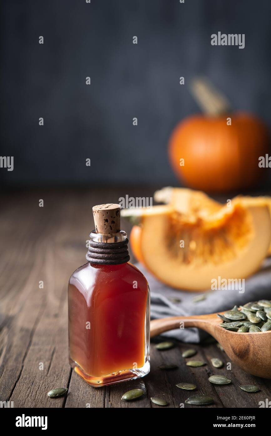 Olio di semi di zucca pressato a freddo in una bottiglia di vetro, decorato con semi sbucciati su un tavolo di legno con spazio per la copia Foto Stock