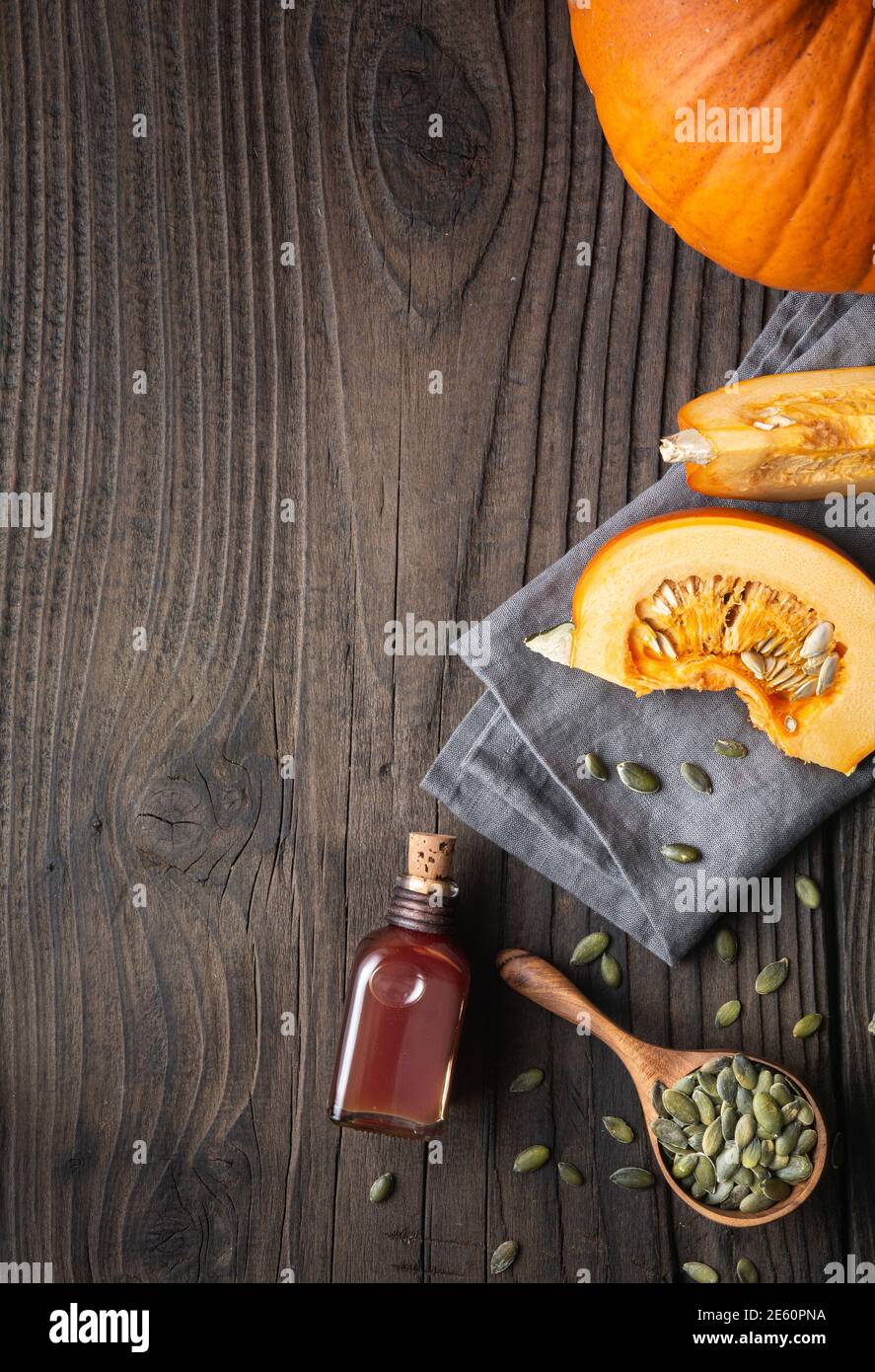 Olio di semi di zucca pressato a freddo in una bottiglia di vetro, decorato con semi sbucciati su un tavolo di legno con spazio per la copia Foto Stock