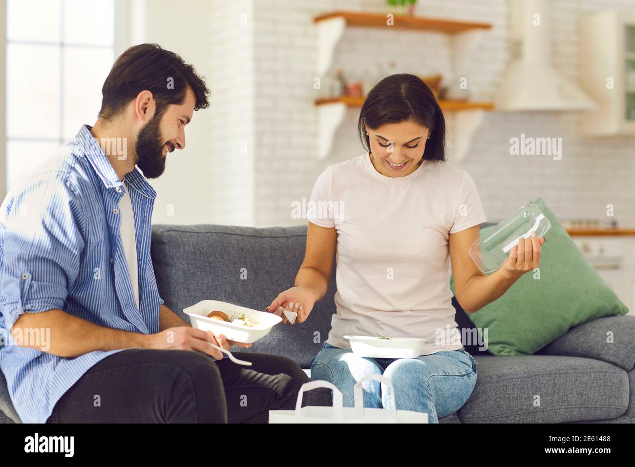 Felice coppia seduta sul divano a casa e sana pranzo ordinato con consegna a domicilio Foto Stock