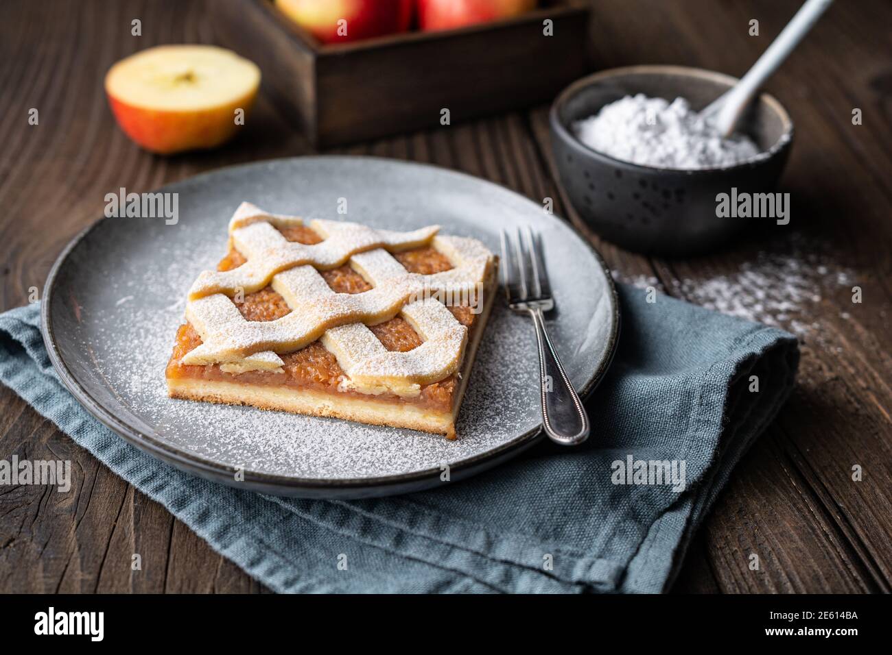 Fetta di torta alla cannella di mele con sommità a graticcio, cosparsa di zucchero in polvere su vecchio sfondo di legno Foto Stock