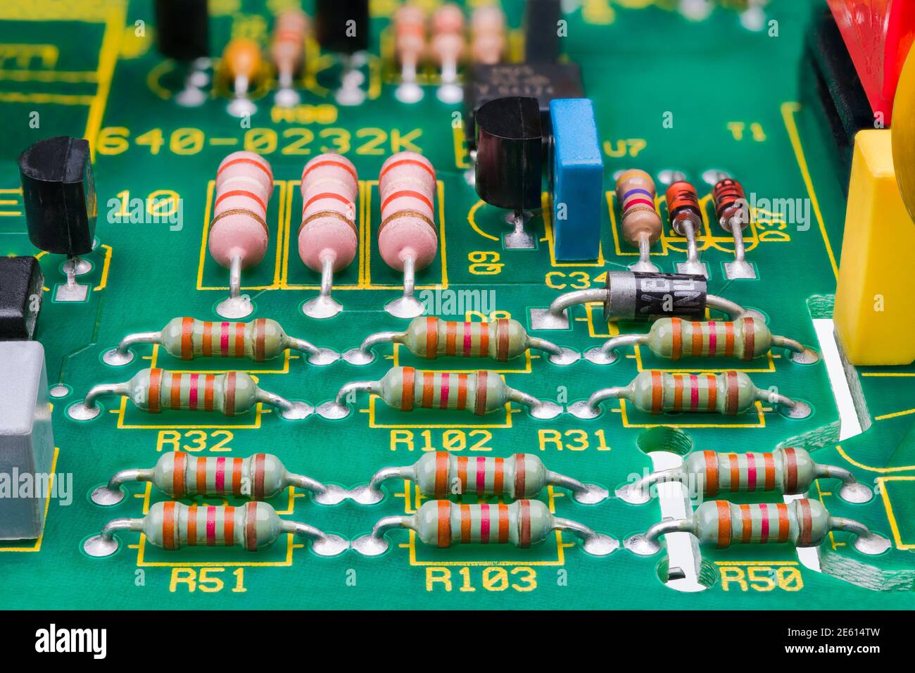 Diversi componenti elettronici sui dettagli della scheda a circuito stampato. Primo piano di resistori, transistor o diodi su circuito stampato verde con traferri di sicurezza. Foto Stock